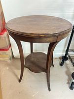 Full view of round wooden table showing legs and lower shelf