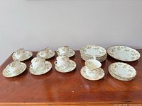 Entire partial set laid out on table showing cups, saucers, two sizes of plates
