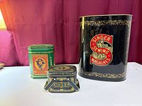 Front view of three advertising tins: large Singer, medium Eaton’s, small Singer