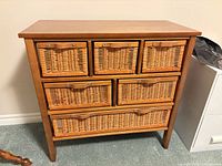 Front view of wood dresser featuring six wicker basket drawers