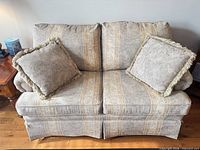 Loveseat with two pillows showing fabric pattern and wear