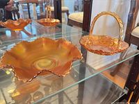 Two marigold carnival glass pieces on shelf