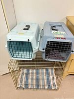 Overall view of two plastic pet carriers stacked on top of wire crate