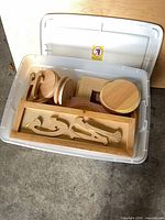 Top view of open bin showing rectangular frame with loose wooden letters and round plaques beneath