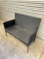 Front angled view of black synthetic wicker loveseat bench