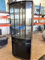 Full view of black curio cabinet showing glass top section and lower storage