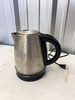 Front view showing stainless body, handle, base and power cord