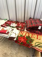 Assorted Christmas linens on table including rugs, seat cushions and towels