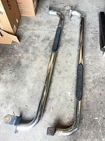 Both chrome nerf bars lying on concrete floor showing full length and end brackets