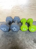 Front view of two grey 10 lb and two green 5 lb Embark dumbbells