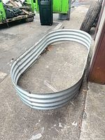 Top angled view of entire galvanized oval raised bed showing size and surface wear