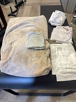 Entire lot: beige blanket and grouped white pillowcases on table