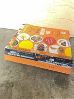 Stack view of all four paperback cookbooks showing spines