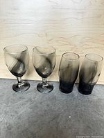All four smoky gray glasses upright on surface