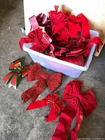 Bin filled with numerous red velvet, satin and glitter bows and ribbon roll