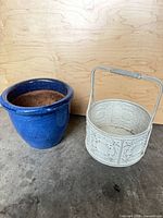 blue ceramic planter and white metal embossed bucket planter side by side