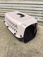 Angled view showing pink top, ventilation holes, black base and metal door