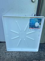 Front view of white plastic drain pan with label showing brand and dimensions