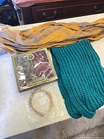 Entire lot overview: boxed pashmina set, teal knit scarf, yellow chiffon scarf, bag with three headbands