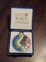 Pendant in open branded box showing front millefiori design.