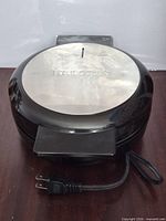 Top view of Kalorik waffle maker showing stainless lid and power cord