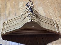 Front view of stacked natural wood hangers showing hooks and engraving