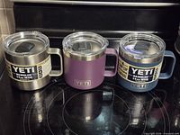 Three Yeti Rambler 14 oz mugs side-by-side showing colors and lids