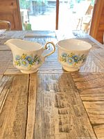 Front view of creamer and sugar bowl showing floral pattern and gold trim