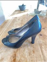 Left side view of both black peep-toe heels showing overall style and heel height