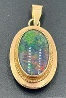 Front view of 14k yellow gold pendant showing opal play-of-colour and rope border