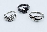 Three sterling silver dolphin rings on white background