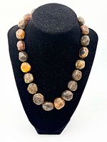 Necklace displayed on bust, front view of graduated amber beads