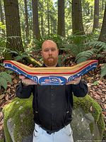 Front view of carved canoe held by person, showing interior and exterior paint