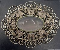 Front view showing rose quartz cabochon and filigree scroll border