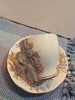 Teacup resting on saucer showing floral pattern and gold trim