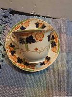 Teacup resting on saucer showing overall pattern and gold rim