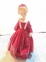 Front view of Royal Worcester porcelain figurine showing red dress, bonnet, facial features