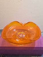 Front view of tangerine art glass bowl showing folded rim and bubble inclusions