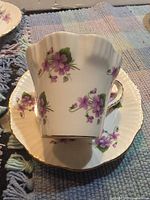 Teacup resting on saucer showing exterior floral design and fluted shape