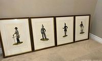 All four framed Arthur Barbosa soldier prints leaning against wall