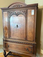 Front view showing full armoire, carved door, drawer, overall design