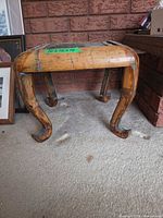 Front angled view of wooden stool showing cabriole legs and distressed finish