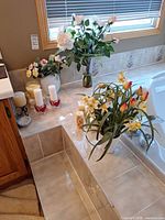 Overall view of flower arrangements, candles, holders and soap on tiled ledge