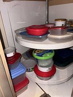 Lazy Susan shelf with multiple plastic containers and two jars