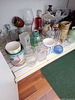 Shelf view of assorted glass, ceramic and metal vases, jars, pitchers and candle holders