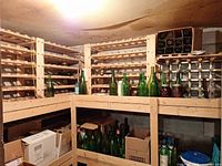 wine racks holding empty green wine bottles and mason jars on top right