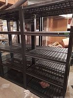 Overall view of black plastic shelving unit showing four vented shelves