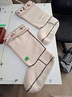 Two cream wool felt stocking boots laid flat showing full size and embroidered cuffs