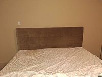 Front view of beige tufted king headboard attached to bed