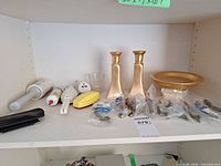 All items on shelf showing candlesticks, dish, votive, cabinet pulls, repair and cleaning tools